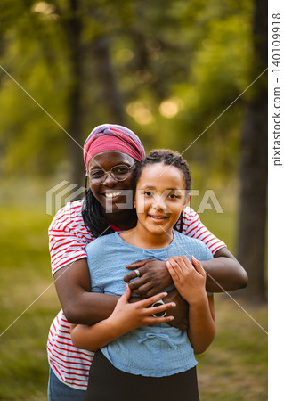 Mother and daughter embracing celebrating family bond outdoors 140109918