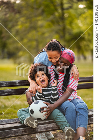 Happy African American family laughing sitting on park bench 140109919