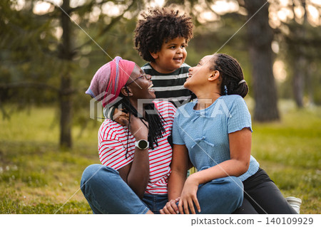 Happy family laughing together while relaxing in park 140109929