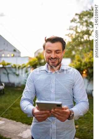 Smiling man holding digital tablet outdoors in backyard 140109947