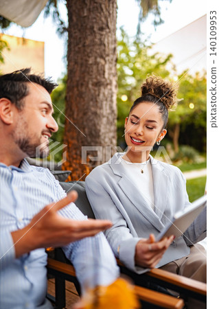 Business colleagues collaborating outdoors during an informal meeting 140109953