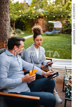 Colleagues using devices during an outdoor business meeting 140109954