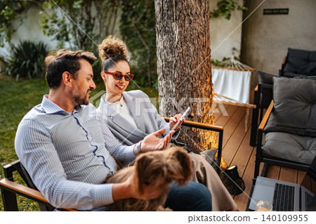 Couple relaxing outdoors with dog using digital tablet 140109955