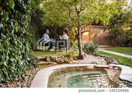 Couple relaxing and enjoying coffee in backyard garden 140109966