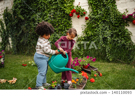 Children watering flowers in the garden together Children watering flowers in the garden together 140110093