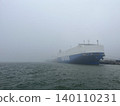 A scene of a harbor shrouded in fog and a large ferry. 140110231