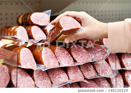 Smoked sausage in hands at store Smoked sausage in hands at store 140110324