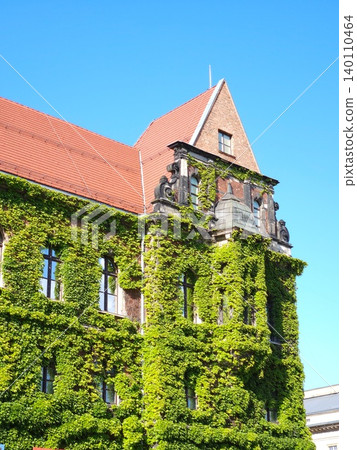 Ivy covered historic building with tiled roof. Concept of urban architecture Ivy covered historic building with tiled roof. Concept of urban architecture 140110464