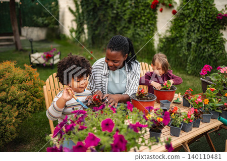 Mother and children planting flowers in backyard garden 140110481