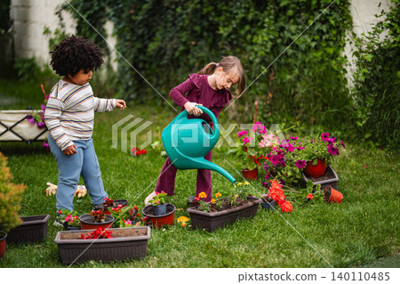 Children learning gardening skills watering flowers in backyard Children learning gardening skills watering flowers in backyard 140110485