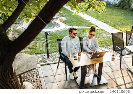 Colleagues collaborating outdoors enjoying remote work lifestyle 140110606