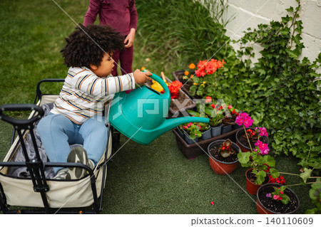 Young child watering plants in wagon during gardening activity 140110609