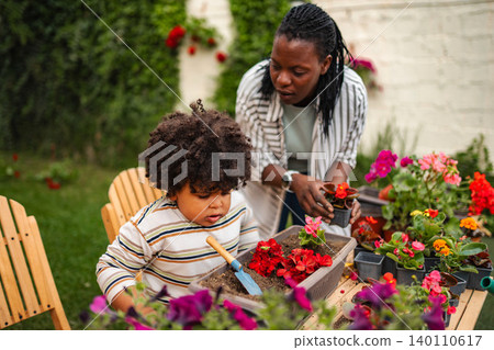 African American mother and son gardening with plants outdoors 140110617