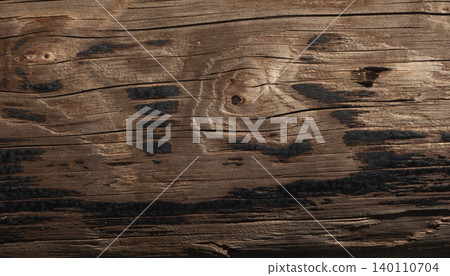 Weathered wooden surface with dark burnt marks and natural grain texture 140110704