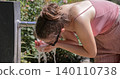 Woman refreshing face with water from public fountain 140110738