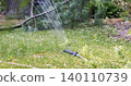 Garden sprinkler irrigating green grass lawn with water 140110739