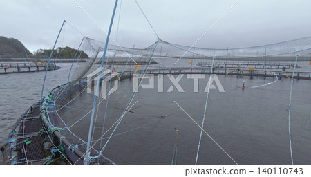 Large fish farm in the water with nets under cloudy sky as background Large fish farm in the water with nets under cloudy sky as background 140110743