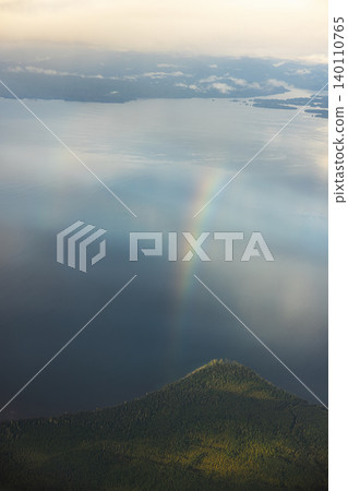 Rainbow arc bending over forest hill and lake 140110765