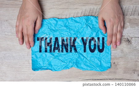 Two female hands hold a blue sheet of crumpled paper with the inscription Thank you Two female hands hold a blue sheet of crumpled paper with the inscription Thank you 140110866