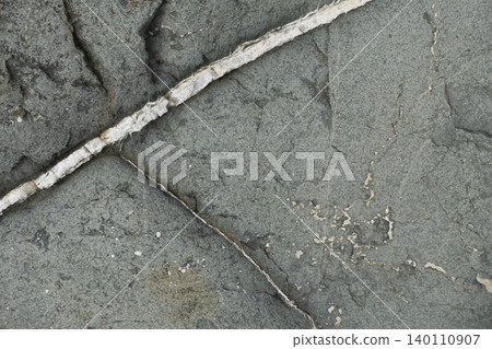 Coastal rock texture with natural quartz vein running through weathered stone surface 140110907
