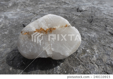 Natural quartz mineral with rusted vein on textured stone surface closeup Natural quartz mineral with rusted vein on textured stone surface closeup 140110915