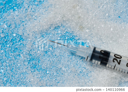 An insulin syringe with an open needle lies on scattered white sugar on a blue background An insulin syringe with an open needle lies on scattered white sugar on a blue background 140110966