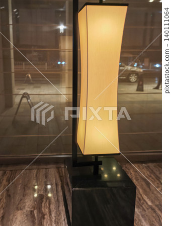 Modern floor lamp with a curved shade illuminated in a stylish interior setting, showcasing a sleek black base and warm light against a marble floor Modern floor lamp with a curved shade illuminated in a stylish interior setting, showcasing a sleek black base and warm light against a marble floor 140111064