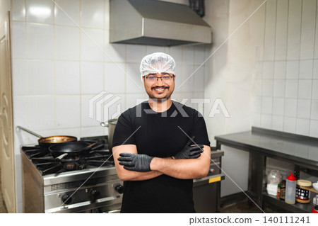 Smiling professional chef standing in commercial kitchen Smiling professional chef standing in commercial kitchen 140111241