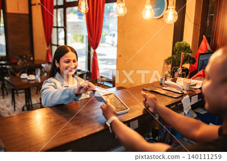 Woman making credit card payment at restaurant counter Woman making credit card payment at restaurant counter 140111259