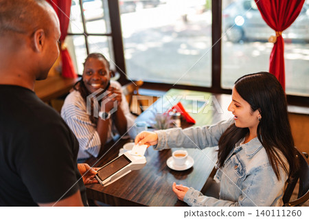 Woman making a payment with her credit card at a cafe Woman making a payment with her credit card at a cafe 140111260