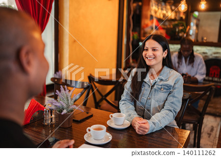Smiling woman enjoying coffee with partner during casual date Smiling woman enjoying coffee with partner during casual date 140111262