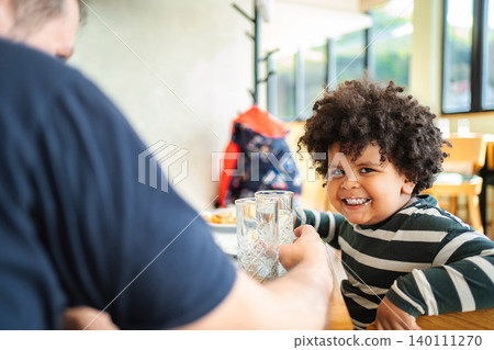 Happy child drinking water at a restaurant with dad 140111270