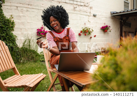 Woman shopping online with credit card outdoors 140111271
