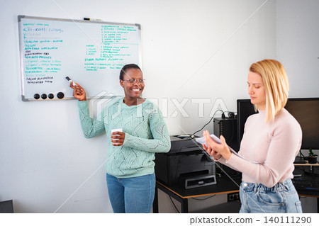 Businesswomen collaborating on project, smiling and discussing in office Businesswomen collaborating on project, smiling and discussing in office 140111290