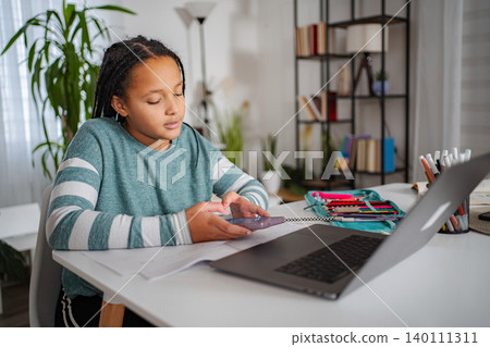 Girl using phone instead of studying, losing focus on laptop Girl using phone instead of studying, losing focus on laptop 140111311
