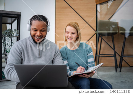 Diverse business people collaborating using technology and taking notes Diverse business people collaborating using technology and taking notes 140111328
