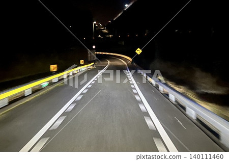 A scene of a sharply curved road at night with reflective panels guiding the viewer's gaze. A scene of a sharply curved road at night with reflective panels guiding the viewer's gaze. 140111460
