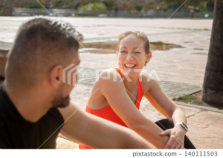 Personal trainer and female client resting and talking after outdoor workout session 140111503