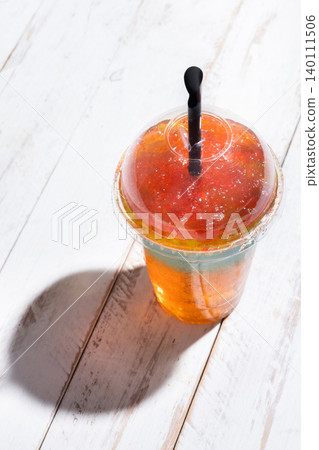 Colorful Frozen Slushie Drink in Plastic Cup on White Wooden Table 140111506