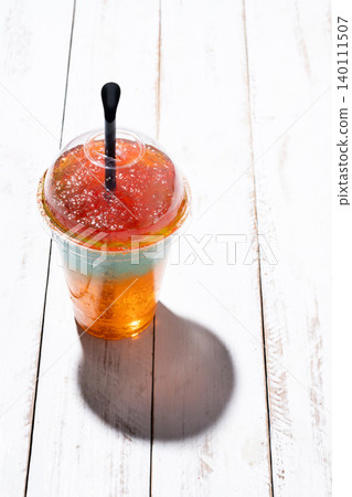 Colorful Frozen Slushie Drink in Plastic Cup on White Wooden Table Colorful Frozen Slushie Drink in Plastic Cup on White Wooden Table 140111507