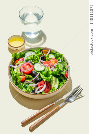 A vegetable salad on a plate on yellow isolated background with shadows. A vegetable salad on a plate on yellow isolated background with shadows. 140111872