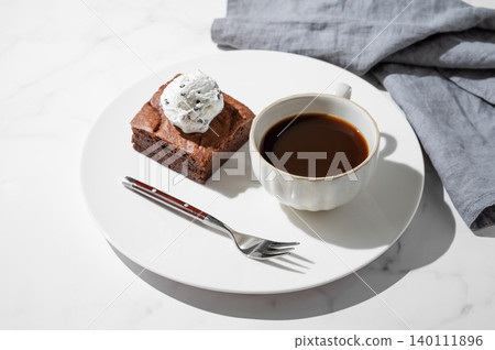 A piece of chocolate brownie with ice cream on a plate and a cup of espresso coffee A piece of chocolate brownie with ice cream on a plate and a cup of espresso coffee 140111896