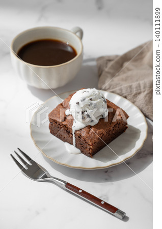 A piece of chocolate brownie with ice cream on a plate and a cup of espresso coffee A piece of chocolate brownie with ice cream on a plate and a cup of espresso coffee 140111899