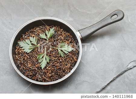 Edible mealworms , lat. Tenebrio molitor, in a frying pan on the stone table. Edible mealworms , lat. Tenebrio molitor, in a frying pan on the stone table. 140111968