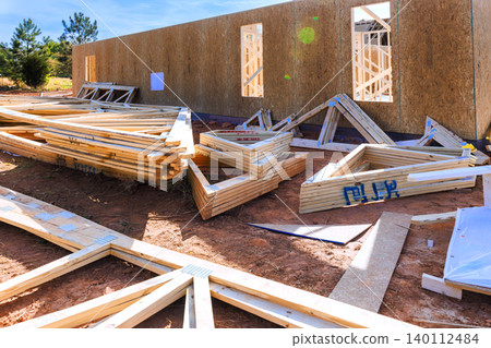 Wooden beams panels are arranged on ground near walls of building under construction 140112484