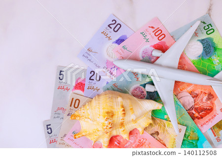 Maldives rufiyaa cash currency banknotes model airplane with seashell placed together for travel theme. Maldives rufiyaa cash currency banknotes model airplane with seashell placed together for travel theme. 140112508