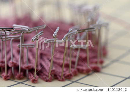 Close Up of Blocking Knitted Fabric with Metal T-Pins on White Close Up of Blocking Knitted Fabric with Metal T-Pins on White 140112642