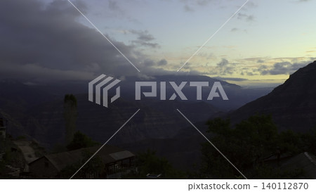Sunset Over Rocky Village And Misty Hills, Village At Night With Mossy Stones And Gentle Valley Fog. Creative Sunset Over Rocky Village And Misty Hills, Village At Night With Mossy Stones And Gentle Valley Fog. Creative 140112870