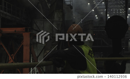 Nighttime Safety Supervisor In Protective Attire Oversees Complex Manufacturing Equipment Operations . Stock clip 140112936