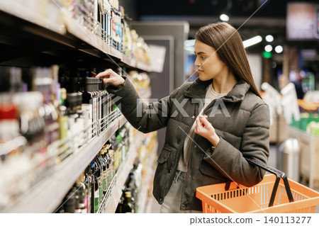 Woman choosing products from a supermarket shelf Woman choosing products from a supermarket shelf 140113277